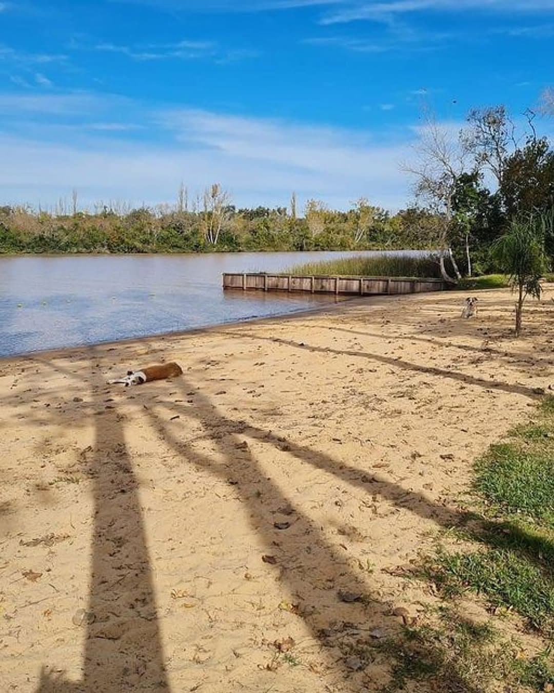 Playa de arena de un lote con su muelle sobre el canal.